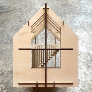 Puede incluir: Un modelo de madera de una casa con un interior detallado, que incluye una escalera y un balc&oacute;n. El modelo est&aacute; hecho de madera clara con detalles en marr&oacute;n oscuro.