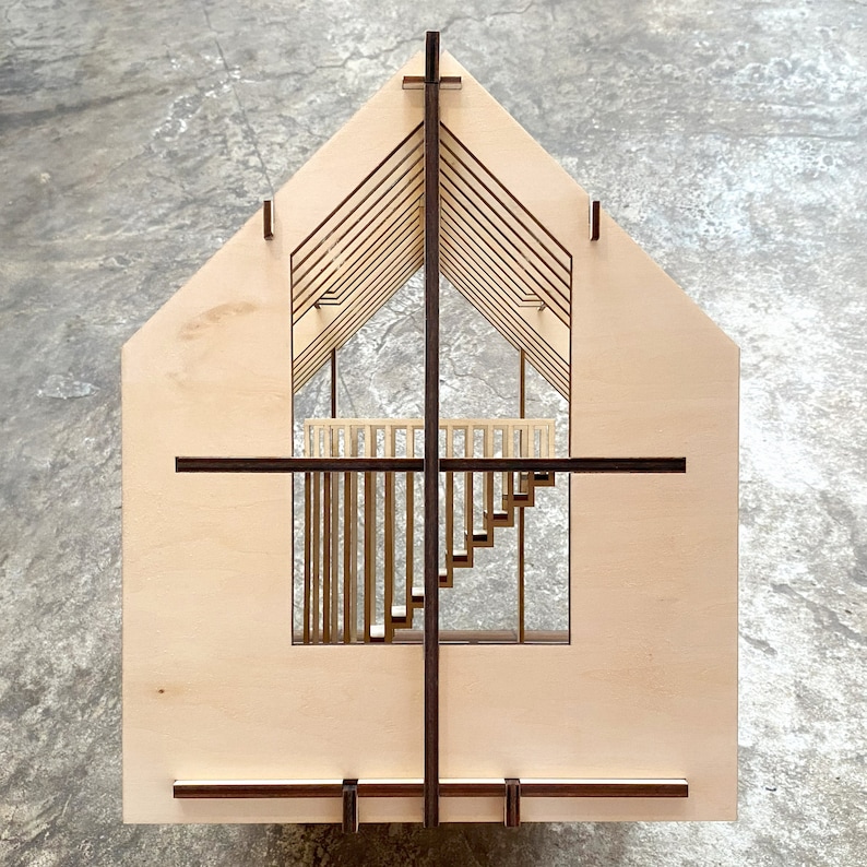 Puede incluir: Un modelo de madera de una casa con un interior detallado, que incluye una escalera y un balc&oacute;n. El modelo est&aacute; hecho de madera clara con detalles en marr&oacute;n oscuro.