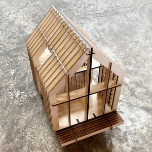 Puede incluir: Un modelo de casa de madera con un interior y exterior detallados. El modelo est&aacute; hecho de madera cortada con l&aacute;ser y presenta un techo, paredes, ventanas y un porche.