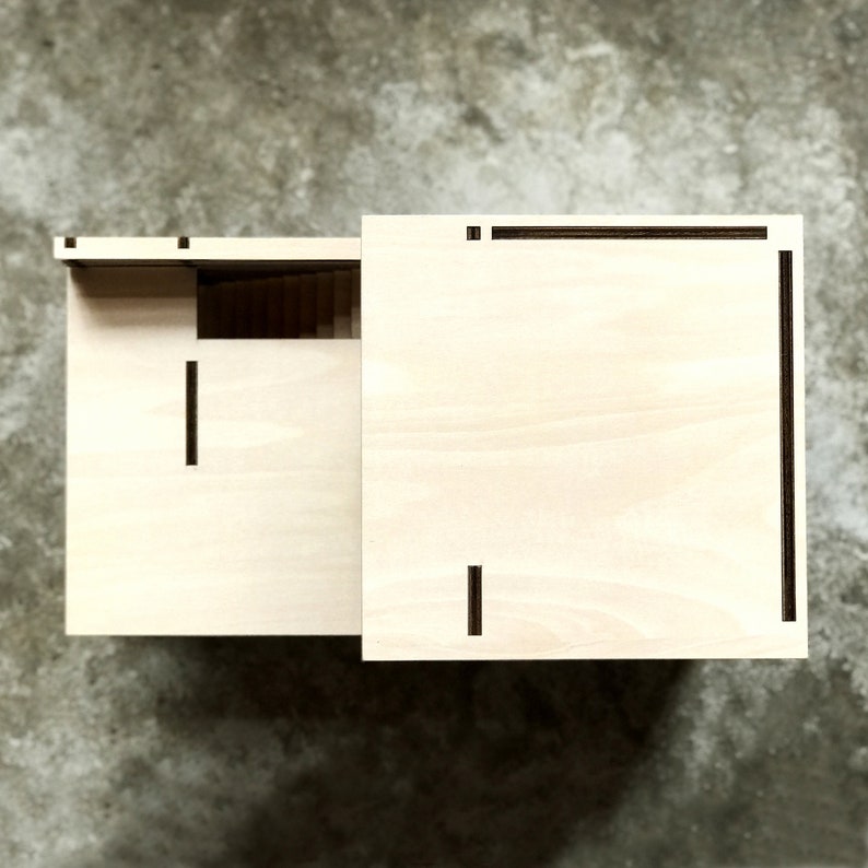 May include: Two wooden boxes with a light wood finish and black lines. The boxes are side by side and have a simple design.