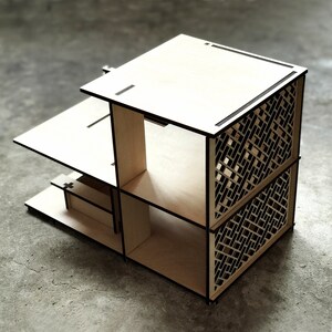 May include: A wooden shelf unit with a geometric pattern on the front. The shelf has three levels and is made of light wood.