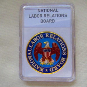 May include: A gold-colored coin with a blue and red seal featuring a bald eagle with a red, white, and blue shield. The seal reads "NATIONAL LABOR RELATIONS BOARD".