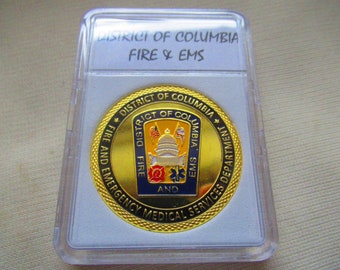 May include: Gold-colored coin with a blue and gold seal featuring the Capitol Building, a fire hydrant, and a medical symbol. The text "DISTRICT OF COLUMBIA FIRE AND EMERGENCY MEDICAL SERVICES DEPARTMENT" surrounds the seal.