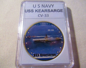 Puede incluir: Una moneda de color dorado con una imagen azul y blanca del portaaviones USS Kearsarge. La moneda tiene el texto "United States Navy" y "USS Kearsarge" en ella.