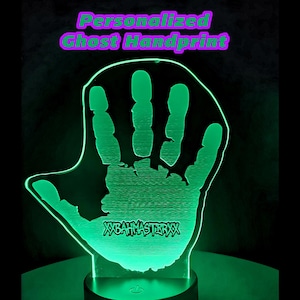 Może przedstawiać: Spersonalizowana lampka nocna z odciskiem dłoni ducha. Odbicie dłoni jest podświetlone na zielono, z tekstem "WEAHMASTERXX" u podstawy. Słowa "Personalized Ghost Handprint" znajdują się nad odciskiem.
