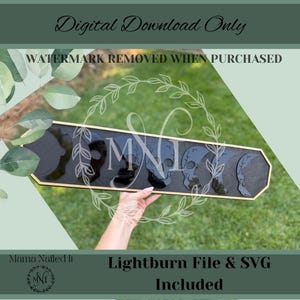 Peut inclure: Une enseigne en bois noir avec une bordure dorée, ornée de motifs de crânes et des lettres "MNI". L'enseigne comprend le texte "Digital Download Only", "Watermark Removed When Purchased" et "Lightburn File & SVG Included".
