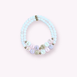 May include: A white beaded bracelet with the words "Lil Sis" and "Big Sis" spelled out in colorful beads.