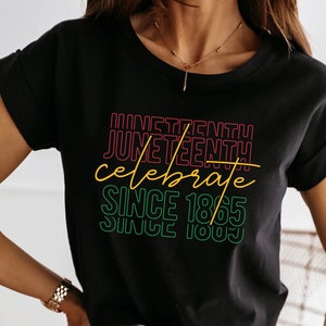 May include: Black t-shirt with a graphic design that says "Juneteenth! Celebrate Since 1865 Since 1983" in a rainbow color scheme.