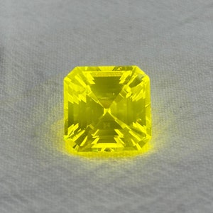 May include: A bright yellow gemstone with a square cut and a faceted design.