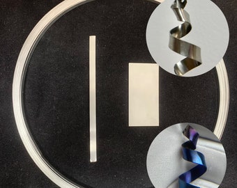 Puede incluir: Un rollo de lámina de metal plateado, una pieza plana de metal plateado y dos bobinas de alambre metálico. Una bobina es plateada y la otra es azul y morada.