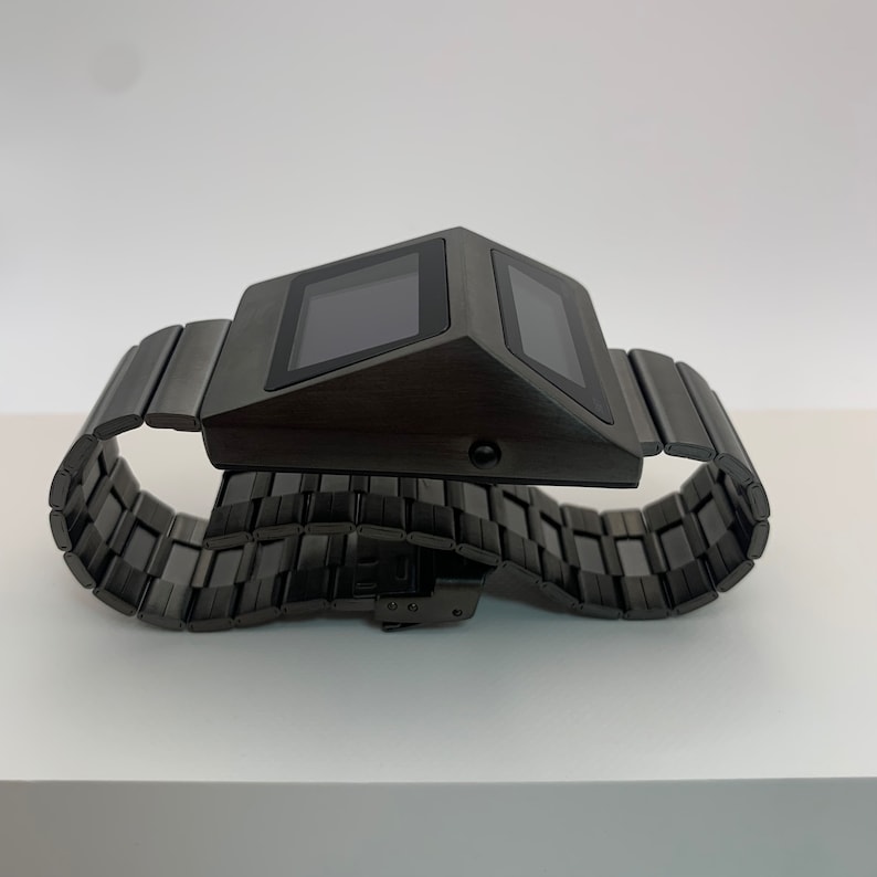 May include: A black digital watch with a metal band. The watch face is rectangular and has a digital display.