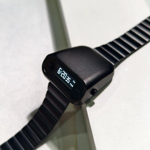 Op de afbeelding: Een zwart digitaal polshorloge met een zwarte metalen band. Het horloge laat de tijd 18:20:35 zien.