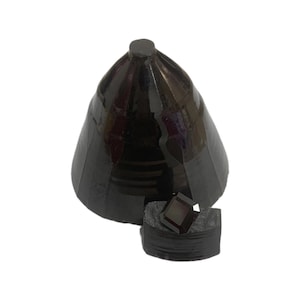 Könnte beinhalten: Ein schwarzer Keramikkegel mit einem kleinen, quadratischen, violett getönten Edelstein im Inneren. Der Kegel ist in zwei Hälften gebrochen, wodurch der Edelstein sichtbar wird.