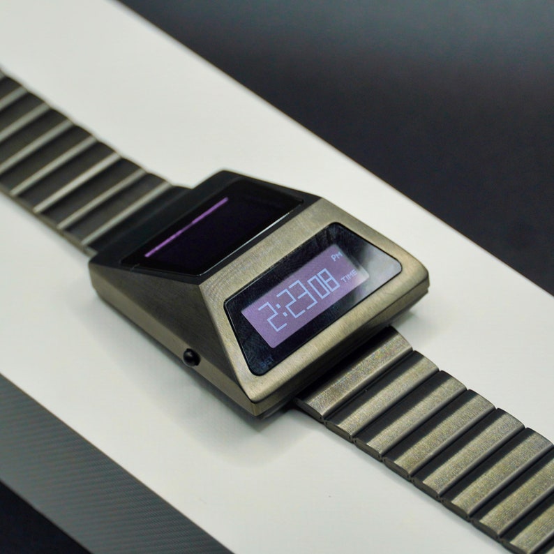 May include: A silver-toned digital wristwatch with a black face and a metal band. The watch face displays the time as 2:23:08 PM.