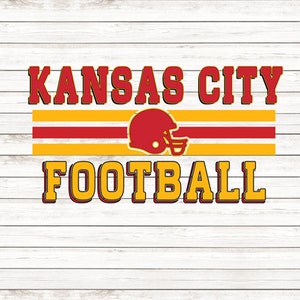 May include: Kansas City Football logo with a red and yellow color scheme. The logo features a football helmet with a red and white design on a white wooden background.