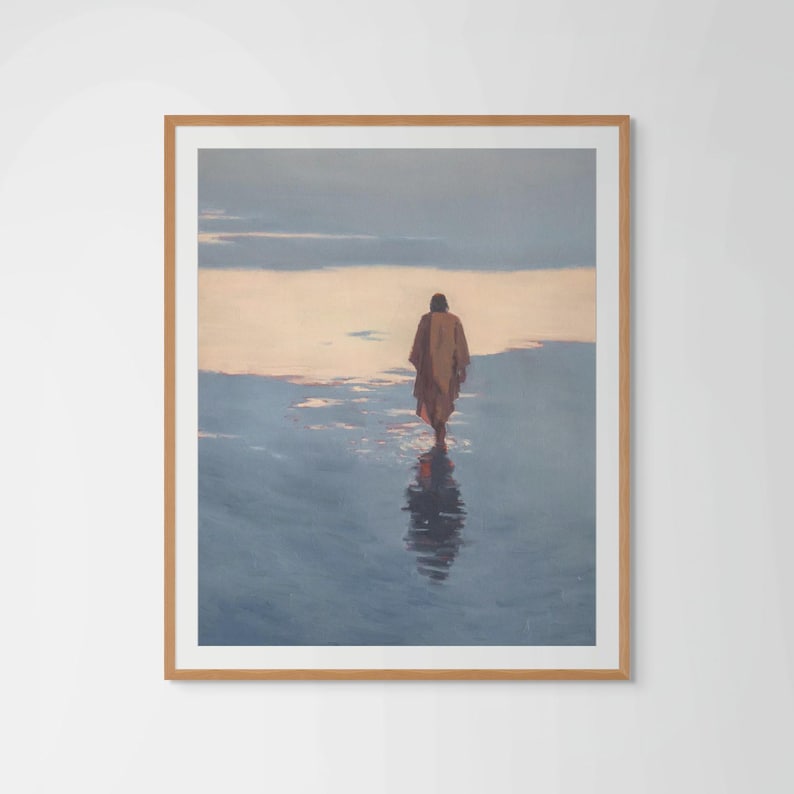 May include: A framed art print depicts a figure walking in water, with a reflection. The figure is wearing a brown robe, set against a backdrop of a dusky sky and water. The artwork is framed in a light brown wooden frame.