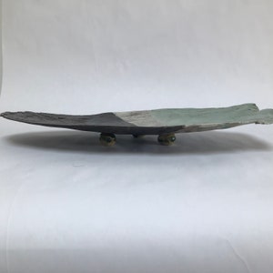 May include: A large, oval ceramic serving tray with a black, white and green glaze. The tray is supported by three small, round ceramic feet.