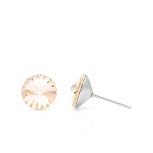 Może przedstawiać: Para srebrnych kolczyków z przezroczystym, jasnoróżowym kryształem w środku.