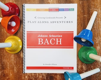 Può includere: Un libro intitolato "Johann Sebastian Bach" con le parole "Growing Gardenside Presents Play-Along Adventures" sulla copertina. Il libro è aperto a una pagina con il testo "Volume 1A" e il nome dell'autore, "Jennifer O'Gwin". Ci sono diversi campanellini di diversi colori su una superficie di legno.