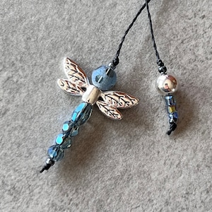 May include: Two silver dragonfly bookmarks with blue crystal beads and black string.