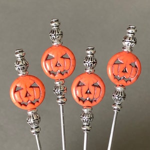 May include: Four orange and silver Halloween themed cocktail picks with jack-o'-lantern faces.