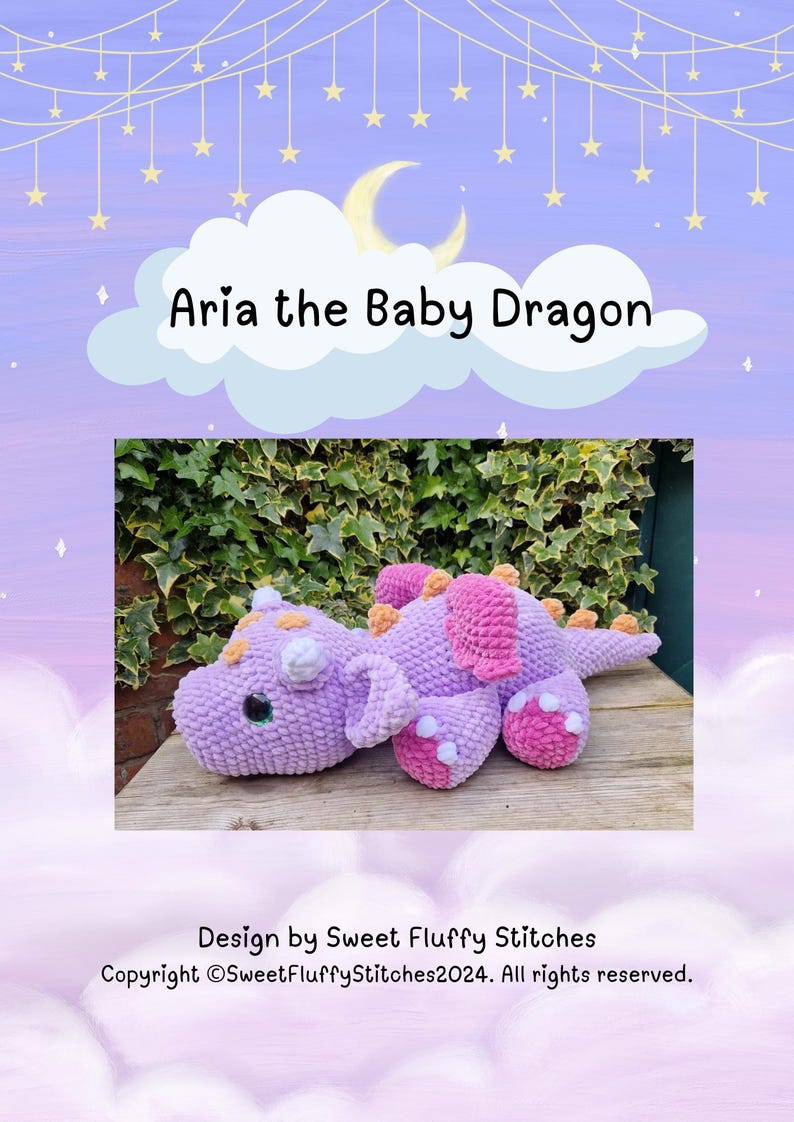 Pu&ograve; includere: Un giocattolo di peluche di drago bambino in crochet viola e rosa con accenti arancioni. Il drago &egrave; sdraiato su una superficie di legno con vegetazione verde sullo sfondo. Il testo "Aria the Baby Dragon" &egrave; sopra l'immagine.
