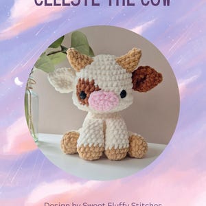 May include: A crocheted plush toy cow named Celeste. The cow is white with brown spots and has a pink nose. The cow is sitting on a white surface.