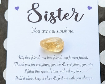 May include: A white card with the words "Sister, You are my sunshine."  A small, yellow citrine crystal is attached to the card. The card also includes the text "My first friend, my best friend, my forever friend. Thank you for everything you do & everything you are. I filled this special stone with all my love. Hold it close, keep it close & feel me with you always. Citrine. Joy. Abundance. Prosperity. www.thebrightheartshop.etsy.com"