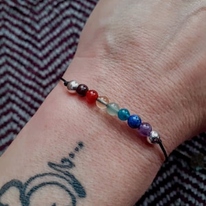Peut inclure: Un bracelet en cordon noir avec sept perles colorées, dont des perles argentées, rouges, orange, vertes, bleues, violettes et argentées.