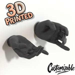 Puede incluir: Dos manos negras impresas en 3D, una con la palma abierta y la otra con el puño cerrado, están montadas en una pared blanca. El texto "3D PRINTED" es visible en la esquina superior izquierda de la imagen. El texto "Customizable" es visible en la esquina inferior derecha de la imagen.