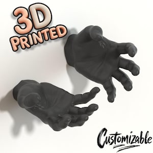 Könnte beinhalten: Zwei schwarze, 3D-gedruckte Hände, die aus einer weißen Oberfläche auftauchen. Der Text "3D PRINTED" ist in einem 3D-Stil mit einem Pfirsich- und Weiß-Farbschema gehalten. Das Wort "Customizable" ist kursiv geschrieben.