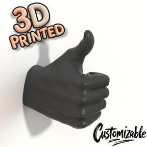 Könnte beinhalten: Eine 3D-gedruckte, mattschwarze Handskulptur mit erhobenem Daumen. Die Worte "3D PRINTED" sind in einer 3D-Schriftart über der Hand, und das Wort "Customizable" ist darunter in Schreibschrift geschrieben.