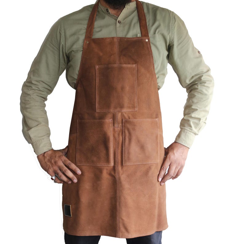 May include: A brown leather apron with two large pockets and a smaller pocket on the chest. The apron has adjustable straps.