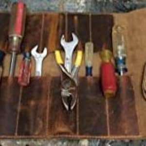 May include: A brown leather tool roll with multiple pockets, holding various tools including screwdrivers, pliers, and wrenches.