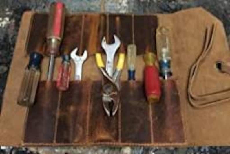 May include: A brown leather tool roll with multiple pockets, holding various tools including screwdrivers, pliers, and wrenches.