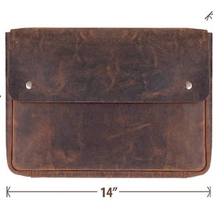 May include: A brown leather laptop sleeve with a flap closure and two metal snaps. The sleeve measures 14 inches wide and 10 inches tall.