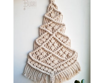 Könnte beinhalten: Ein beigefarbener Makramee-Weihnachtsbaum-Wandbehang mit einem Holzring oben und einem Quasten unten. Der Baum ist mit einem Rautenmuster gearbeitet und hat Fransen an den Rändern.