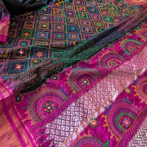 May include: A white ceramic mug with a black handle and the text "But First, Coffee" in a bold, black font. The mug is set against a blurred background, suggesting a cozy setting.