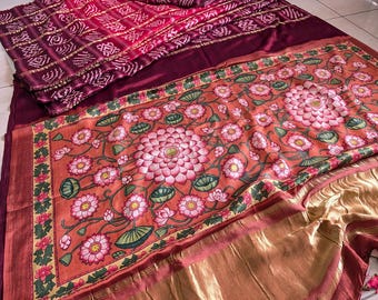 Può includere: Un tessuto vibrante con un motivo floreale di fiori di loto rosa su sfondo arancione. Il tessuto ha una base bordeaux con una sezione a fantasia nei toni del rosa e del bordeaux. I bordi sono rifiniti con bordi dorati.