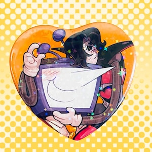 Puede incluir: Botón en forma de corazón con un personaje de dibujos animados sosteniendo un televisor. El personaje tiene cabello negro, bigote y viste un atuendo morado y marrón. El fondo es amarillo con lunares blancos.