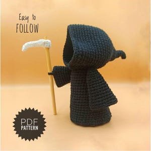 Puede incluir: Una muñeca amigurumi de la Muerte Negra de ganchillo que sostiene una guadaña blanca. La muñeca está de pie sobre una superficie marrón. El texto "Easy to FOLLOW" está en la esquina superior izquierda de la imagen. El texto "PDF PATTERN" está en la esquina inferior izquierda de la imagen.