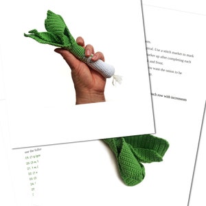 May include: A crochet leek toy with green leaves and a white stem. The toy is held in a hand. The instructions for crocheting the leek are written in black text on a white background.