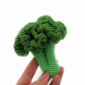 May include: A green crocheted broccoli toy. The broccoli is made with a textured yarn and has a realistic shape.