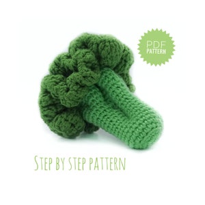 May include: A crocheted broccoli plush toy in green. The toy is made with a textured yarn and has a realistic shape. The image includes the text "PDF PATTERN" and "STEP BY STEP PATTERN".