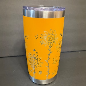 May include: A yellow stainless steel tumbler with a black and white sunflower design. The tumbler has a lid.