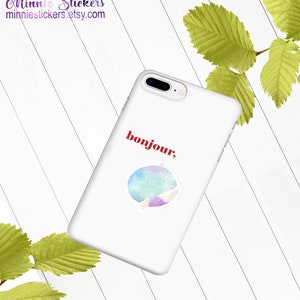 May include: White phone case with a watercolour-style sticker of a galaxy with the word "bonjour" in red text.