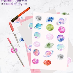 May include: A sheet of stickers featuring watercolour illustrations of planets with rings. The planets are in various colours, including blue, green, pink, purple, and grey. The stickers are perfect for adding a touch of whimsy to your planner, journal, or laptop.