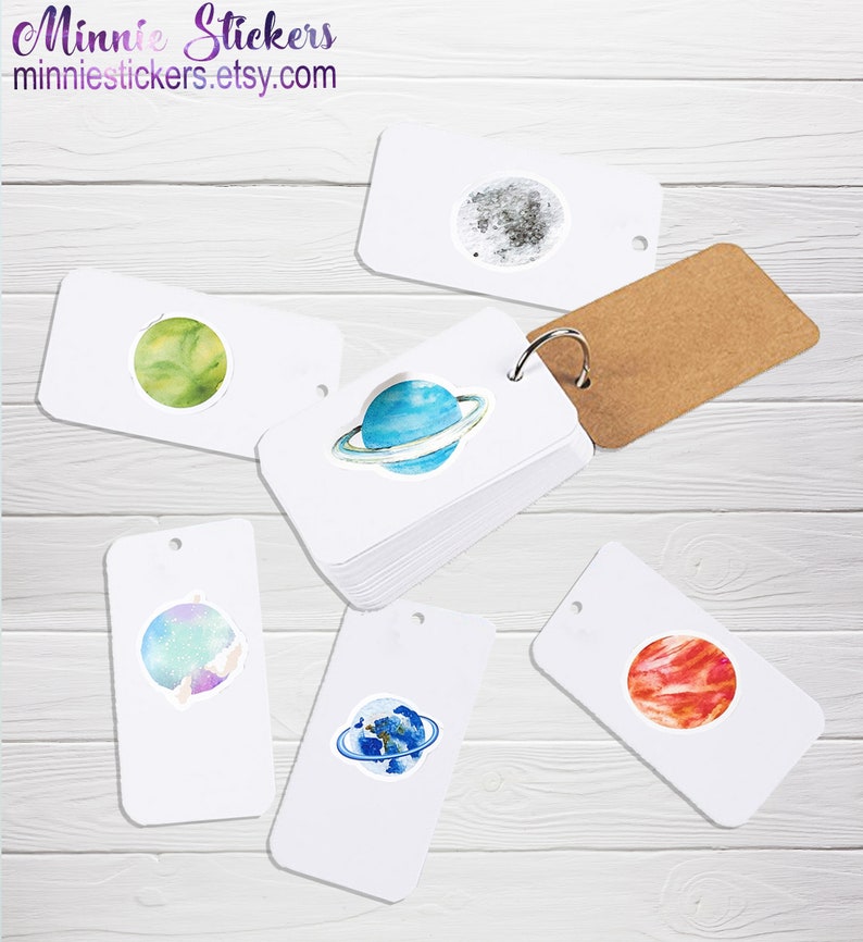May include: A set of six white cardstock stickers featuring watercolour illustrations of planets and moons. The stickers are arranged on a light wood background. The stickers are perfect for adding a touch of whimsy to your planner, journal, or laptop.