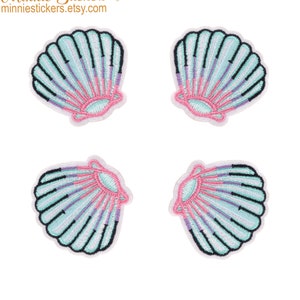 Puede incluir: Cuatro parches termoadhesivos en forma de concha de mar de colores pastel. Las conchas son de color azul claro con detalles en rosa y morado.
