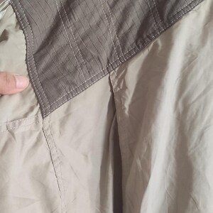 May include: A beige jacket with a brown patch on the shoulder. The patch has a textured design.